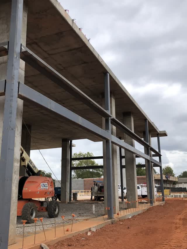 Structural steel frame erected alongside a concrete podium structure
