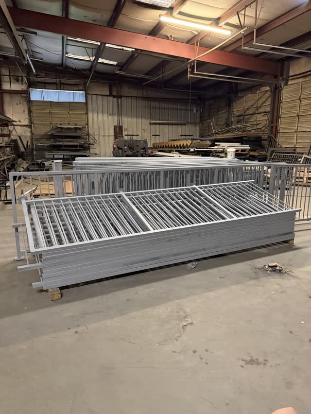 Galvanized steel guardrail sections stacked inside the fabrication shop
