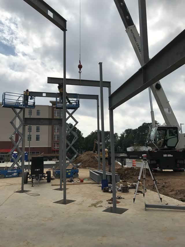 A steel column being lifted into place by crane on a jobsite