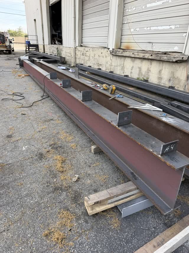 Primed steel beams laid out on the ground before erection