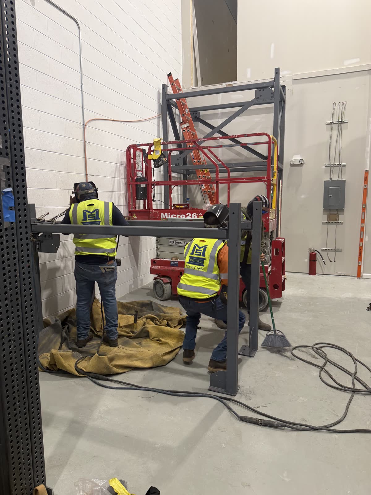 Two More Steel crew members in high-visibility vests setting steel from a lift