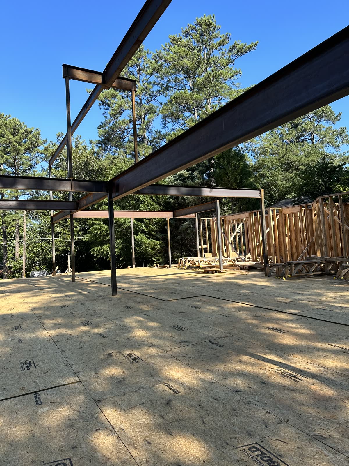 Steel canopy beams standing against open sky on a cleared site