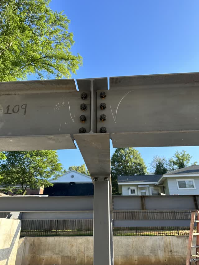Bolted steel beam splice with the fabrication piece mark written on the web
