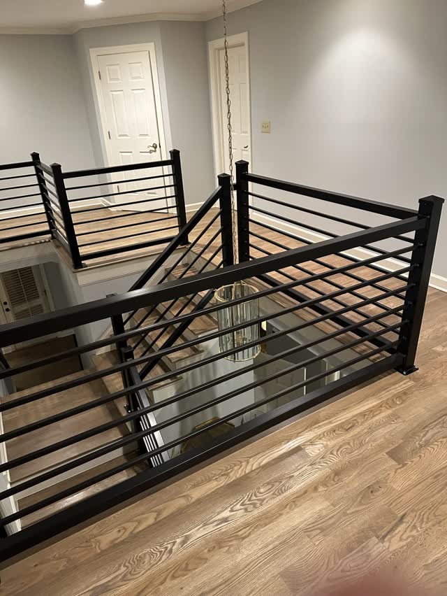 Modern black horizontal bar steel guardrail on a hardwood landing