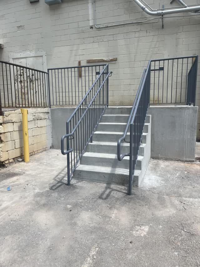 Exterior steel stair with guardrail against a warehouse wall