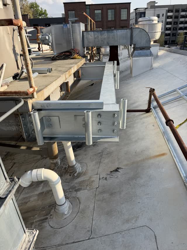 Bolted steel supports carrying rooftop mechanical equipment and pipe