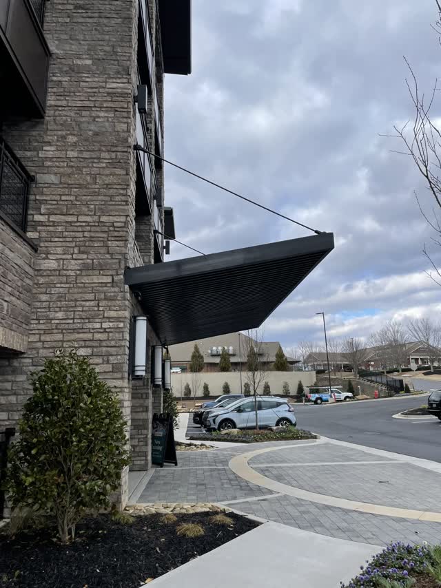 Cantilevered steel entry canopy projecting from the corner of a multi-family building