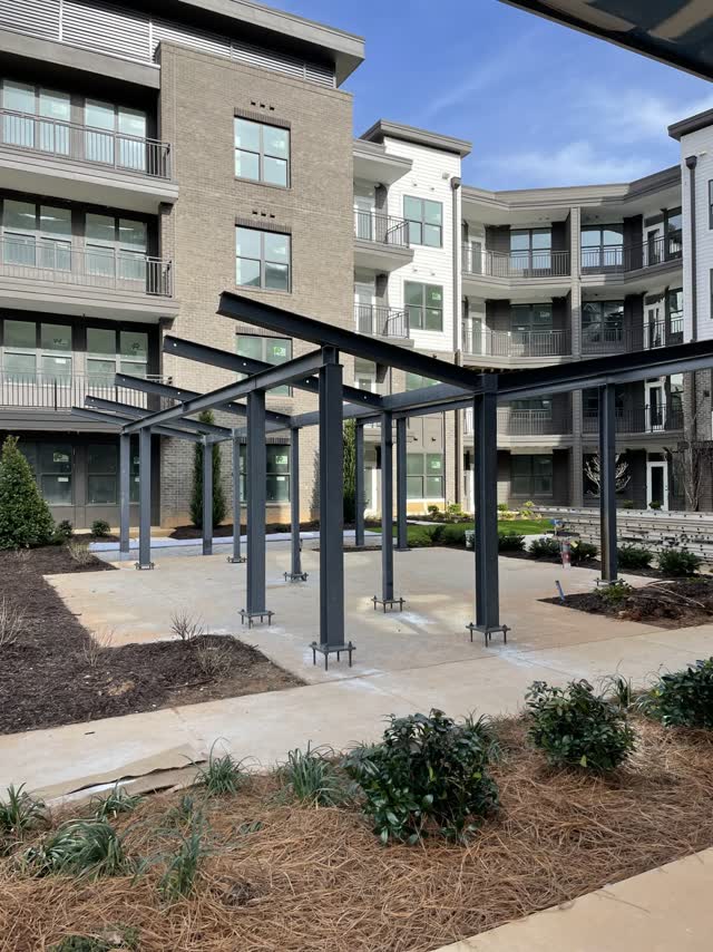 Steel pergola frames standing on base plates in an apartment courtyard