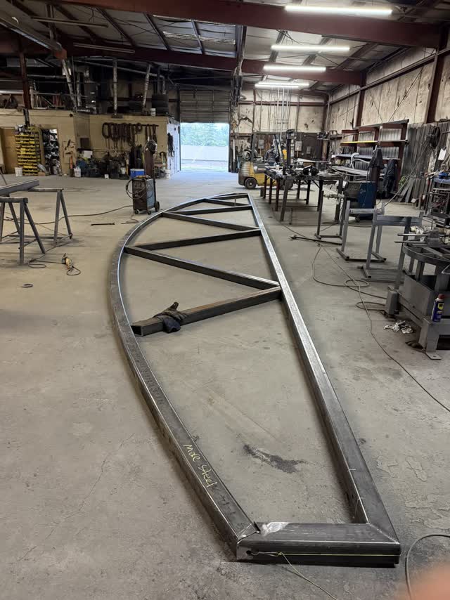 A custom curved steel section laid out on the fabrication shop floor
